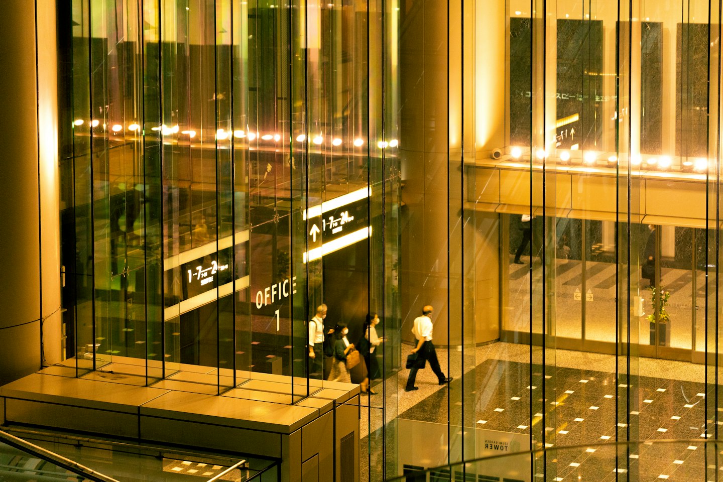 Professionals walk across the polished floor of an office lobby.