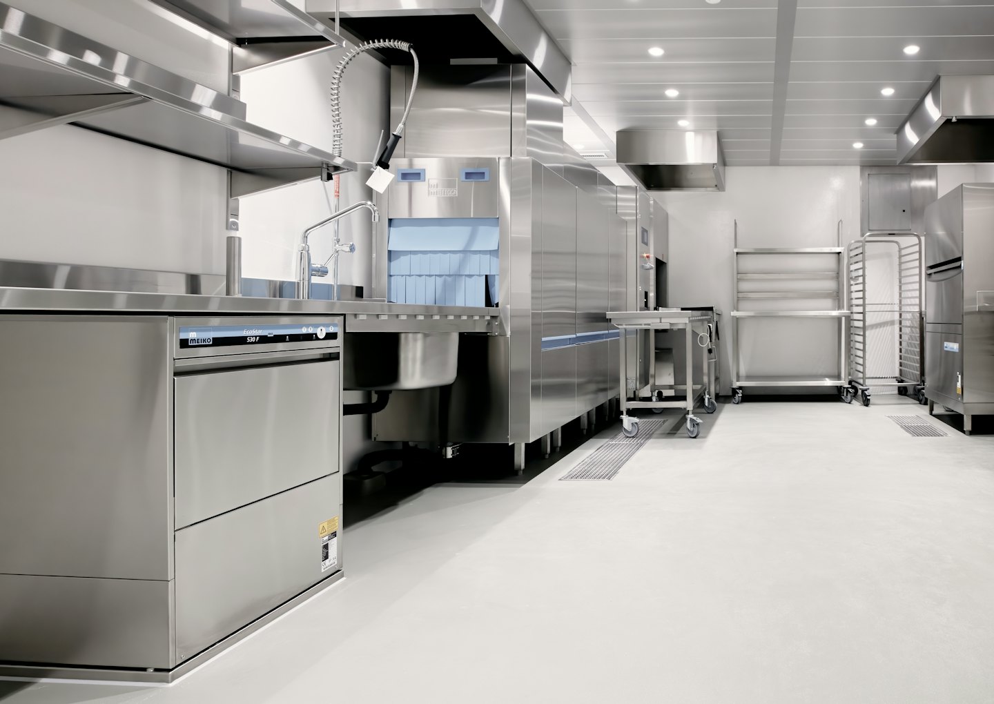 Commercial kitchen with stainless steel appliances and utility carts.