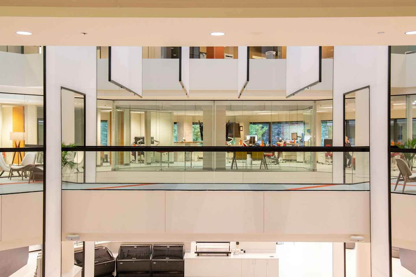 Modern office atrium with glass-walled spaces and contemporary furniture.