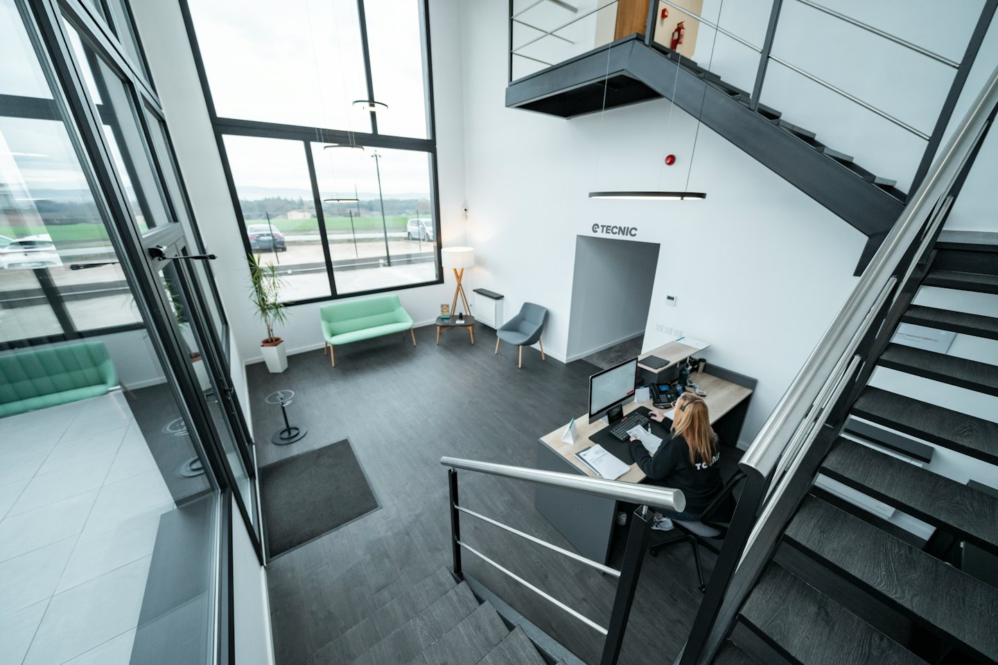 Receptionist working at a computer in a modern office lobby.