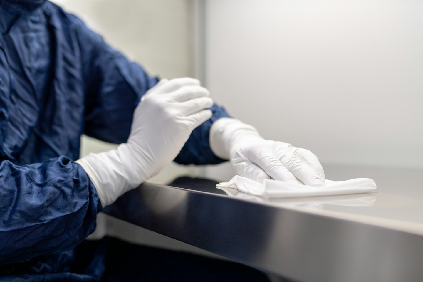 Person in blue suit wipes down a counter with a cloth.
